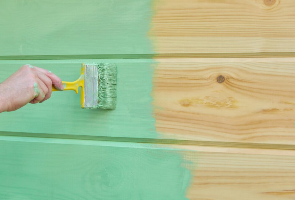 Applying paint wooden surface. Man hand with brush closeup. Painting wood wall.